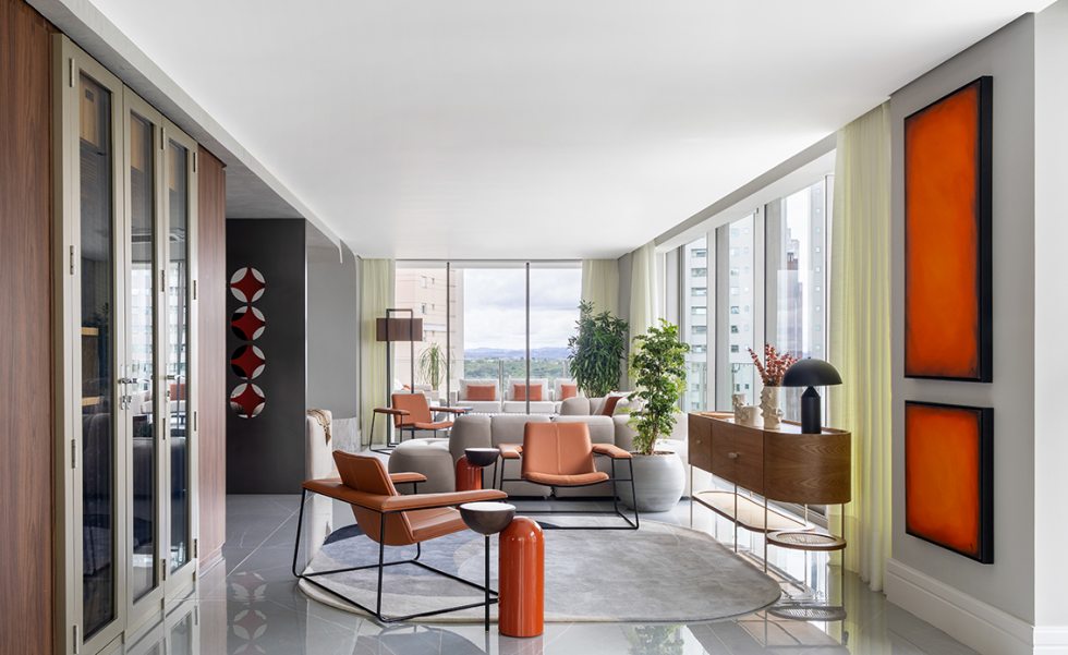 Estar, jantar e varanda gourmet formam um único ambiente, marcado pela continuidade visual e pela entrada abundante de luz natural. À esquerda, a adega climatizada  foi embutida de forma  discreta, reforçando a proposta de funcionalidade integrada ao uso cotidiano.