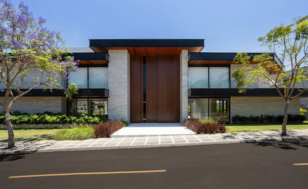 O ripado de concreto, protagonista da fachada voltada para a face sul, imprime movimento à superfície praticamente cega da casa. Além de valorizar a textura e trazer dinâmica ao volume fechado, o material também atua como elemento de proteção, controlando a insolação e reforçando a privacidade.