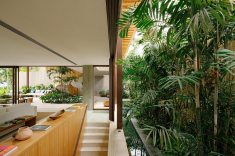 A separação entre áreas sociais e íntimas é marcada por jardins internos e espaços de circulação, que mantêm a ventilação e a iluminação natural presentes em diferentes pontos da residência.